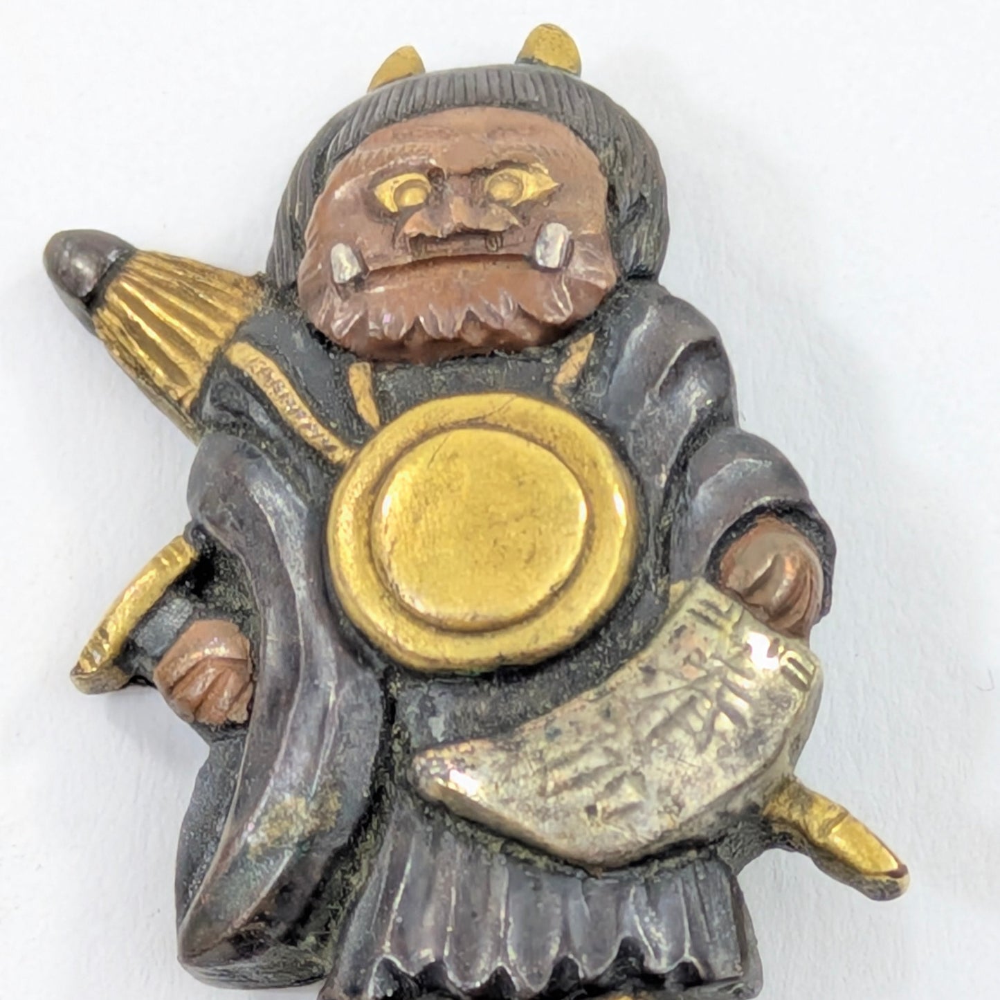 Menuki Oni Dressed as Monk with Drum and Scroll Japan, Edo period, mixed-metal with gilt highlights LS108